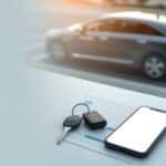 Car keys and paperwork on a bank desk with a blurred car outside; clean space for headline.